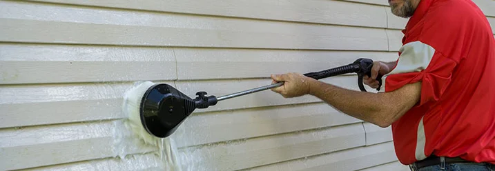 Person reinigt Fassade mit Bürste